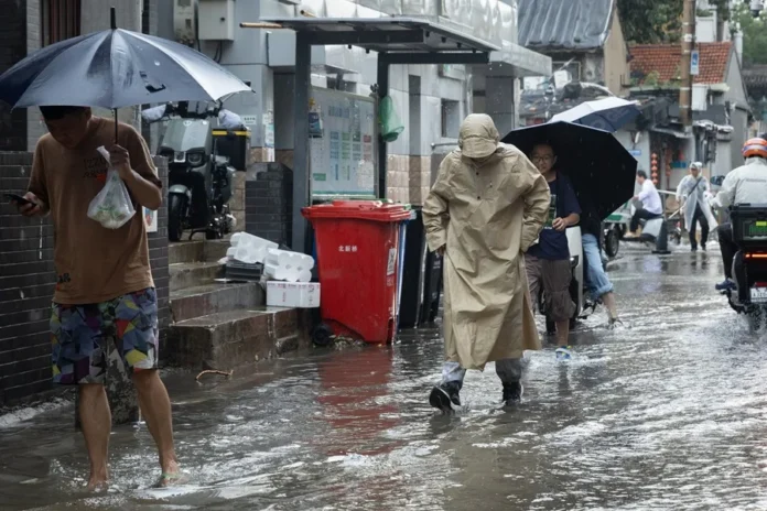 Varias personas caminan por una calle de Pekín en pleno temporal de lluvias. China, EFE/EPA/Jessica Lee